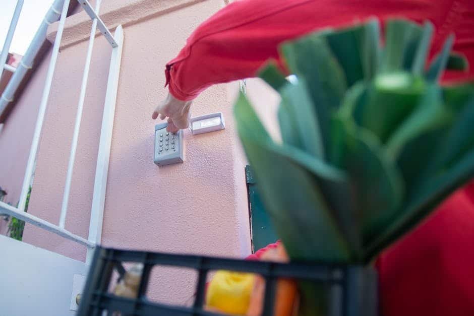 Maison individuelle moderne en France avec volets fermés, lumières allumées en soirée et système d’alarme visible, illustrant une habitation sécurisée pendant les vacances