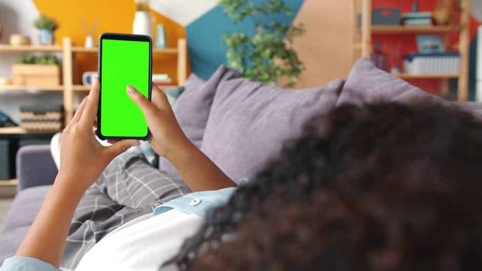 Femme utilisant une application d’autodétection sur son smartphone dans un salon moderne en France, démontrant la gestion de la sécurité de la maison à distance.