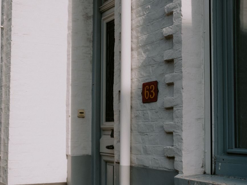 Gros plan sur un détecteur de mouvement installé au-dessus d’une porte d’entrée de maison en France, éclairage extérieur allumé, exemple concret de sécurité passive