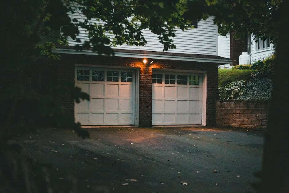 Chemin de jardin et zone de garage d’une maison française bien éclairés la nuit, avec projecteurs LED et appliques murales, illustrant le positionnement optimal des luminaires extérieurs