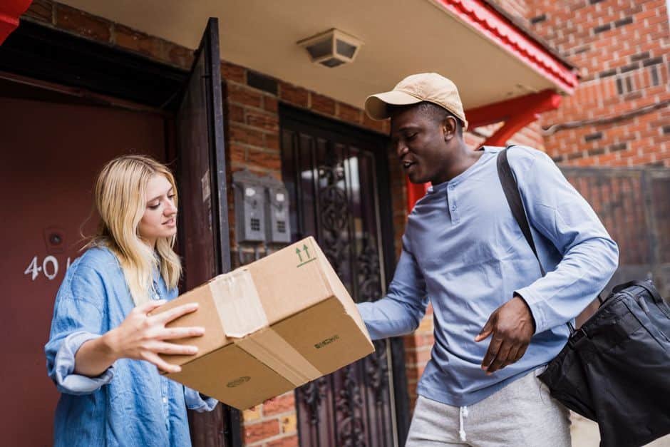 Réception d’un colis à la porte d’une maison française avec une sonnette vidéo connectée visible, illustrant la gestion pratique des livraisons et la surveillance à distance