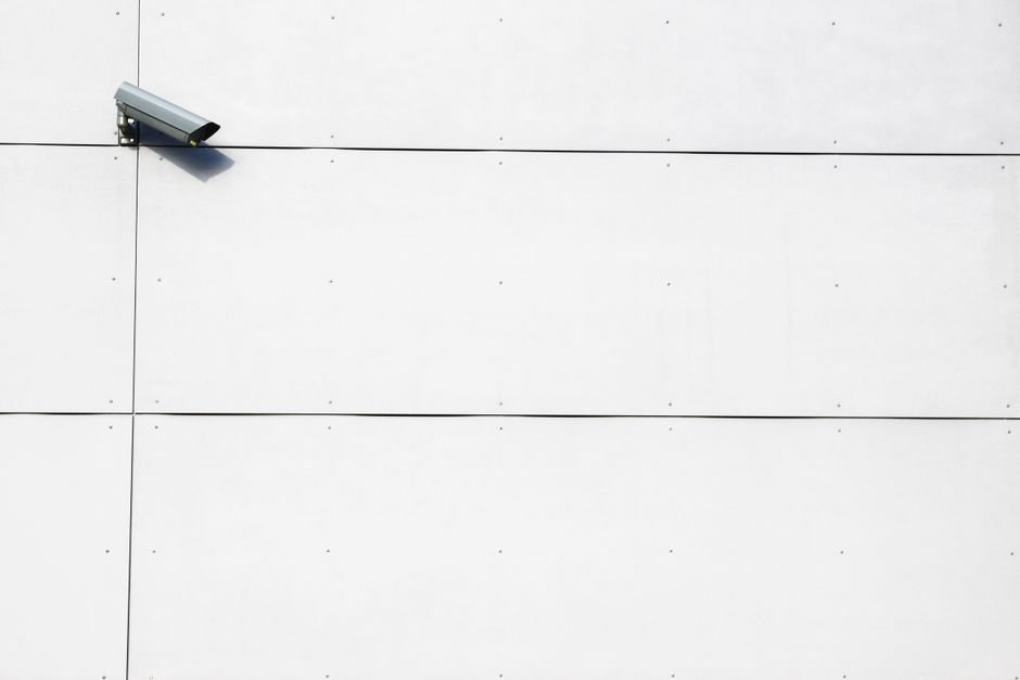 Maison moderne en France équipée de caméras de sécurité, avec une personne tenant un smartphone affichant une application de vidéosurveillance connectée.