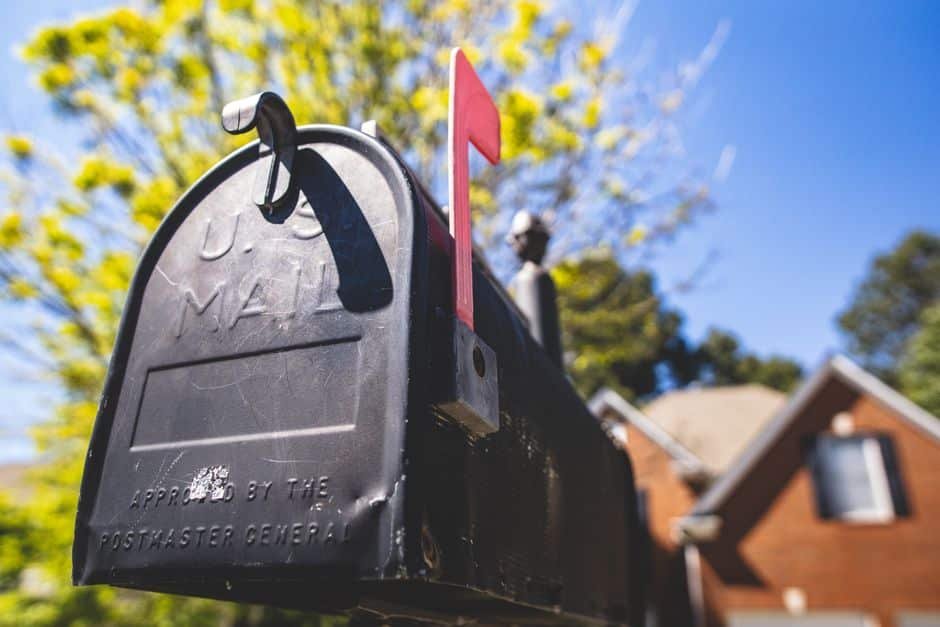 Voisin récupérant le courrier devant une maison en France, bonne pratique pour simuler une présence et sécuriser son domicile lors d’une absence prolongée