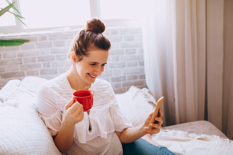 Femme consultant les alertes de son système d’alarme sur son smartphone dans un salon français moderne, avec une sirène d’alarme visible, démontrant la continuité des notifications même sans internet fixe.