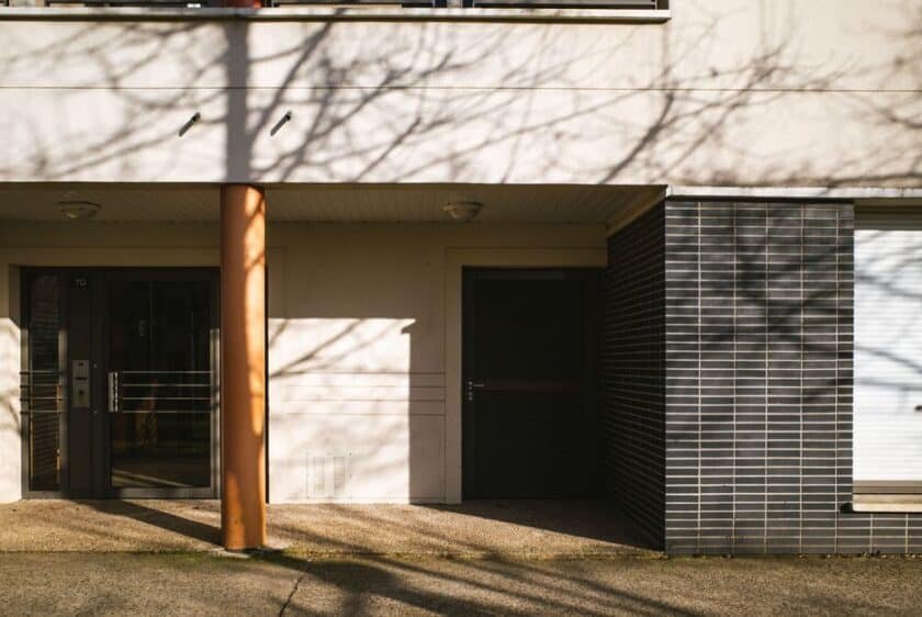 Entrée d’un immeuble résidentiel moderne en France, illustrant les accès à sécuriser pour une alarme appartement efficace